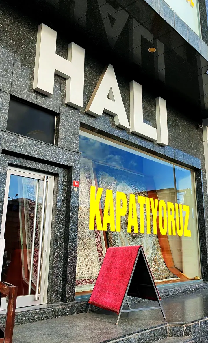MD Halı cephesi: büyük HALI harflerinin altında, vitrin camında sarı harflerle KAPATIYORUZ yazısı